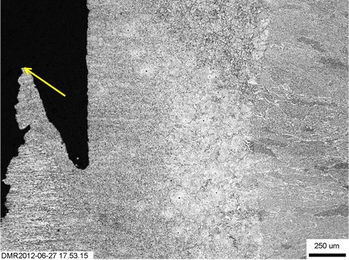Figure 16. Initiation region (shown by arrow) of fractured W01 specimen from just behind the fatigue precrack tip 